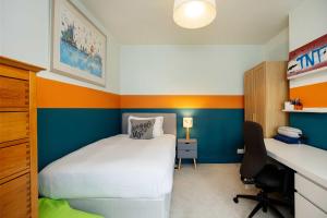 a small bedroom with a bed and a desk at Veeve - Golds and Greens in London