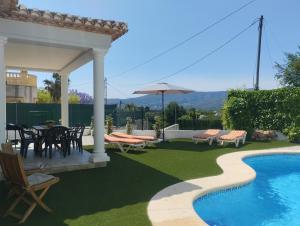 a patio with a table and chairs and a swimming pool at Villas Benicadims - BTB in Beniarbeig