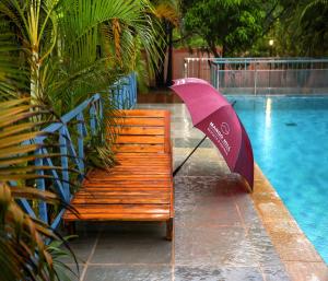 a bench with an umbrella next to a swimming pool at Mango Hill La Serene Puducherry in Pūrnānkuppam