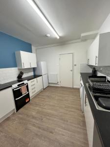 a kitchen with white cabinets and a black counter top at Spacious 5-Bedroom Urban Haven in Luton