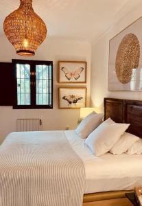 Un dormitorio con una cama con sábanas blancas y una lámpara de araña. en Villa Lavanda by Época Suites, en El Castillo de las Guardas