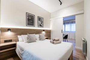ein Schlafzimmer mit einem großen weißen Bett und einem Stuhl in der Unterkunft Exclusive Apartments Barcelona 4 personas St Pere in Terrassa