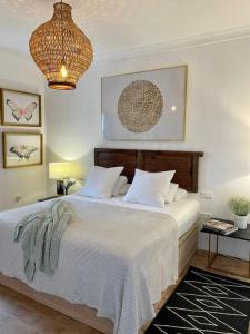 a bedroom with a bed with white sheets and a chandelier at Villa Lavanda by Época Suites in El Castillo de las Guardas