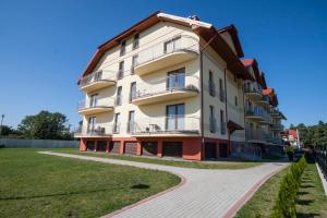 a large white building with a walkway in front of it at Apartament Trap in Karwia