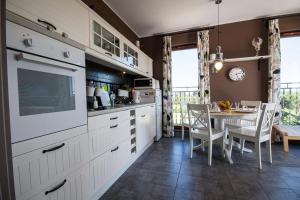 a kitchen with white cabinets and a table with chairs at Apartament Trap in Karwia