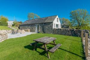a picnic table in the grass in front of a stone building at Melin-Byrdir in Dyffryn