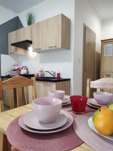 uma cozinha com uma mesa com tigelas e pratos em Apartamenty & Pokoje pod Gruszą em Kudowa-Zdrój