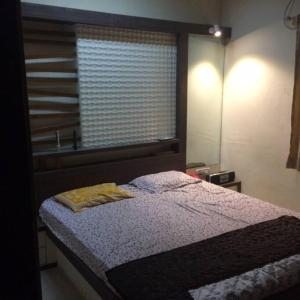 ein Schlafzimmer mit einem Bett mit einem Fenster und einem Bett sidx sidx sidx in der Unterkunft Luxurious 2BHK bunglow with garden in Solapur