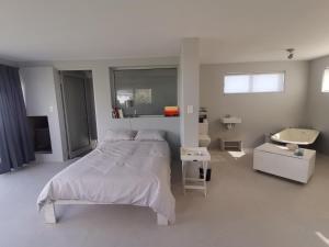 ein weißes Schlafzimmer mit einem Bett und einem Waschbecken in der Unterkunft Betty's Bay Cottage in Bettyʼs Bay