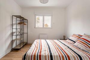1 dormitorio con 1 cama con manta a rayas en Les Chalets du Mancel - Chalet Vakiry - 500 m Bouleries Jump , 10 min du circuit des 24h, en Parence