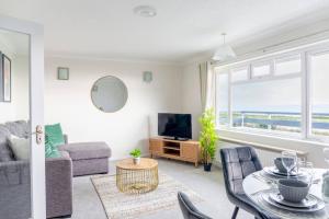 uma sala de estar com um sofá, uma mesa e uma televisão em Breath Taking Sea View 2 bedroom Sleeps 6- Parking em Bournemouth