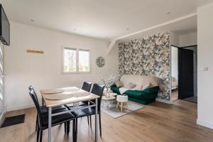 a living room with a table and a green couch at Les Chalets du Mancel - Chalet Vakiry - 500 m Bouleries Jump , 10 min du circuit des 24h in Parence +15 photos