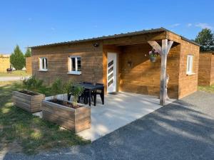 Cabaña de madera con mesa delante en Les Chalets du Mancel - Chalet Vakiry - 500 m Bouleries Jump , 10 min du circuit des 24h, en Parence