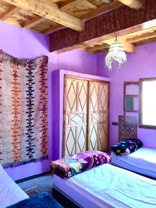 um quarto roxo com 2 camas e um lustre em Atlas Imsker em Marrakech