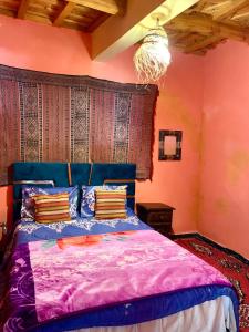 a bedroom with a bed with purple sheets and a chandelier at Atlas Imsker in Marrakech