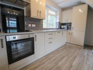 a kitchen with white cabinets and a stove top oven at Woodside in Wrexham