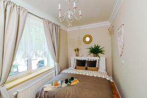 a bedroom with a bed with a chandelier and a window at Apartamenty Colobrzeg Sweet Home in Kołobrzeg