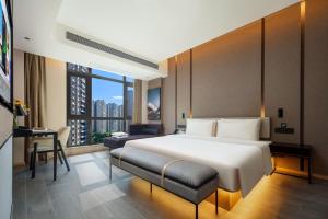 una camera d'albergo con un grande letto e una scrivania di Atour Hotel Meizhou West Station R&F Center a Meizhou