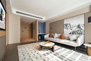 sala de estar con sofá blanco y mesa en Atour Hotel Meizhou West Station R&F Center en Meizhou