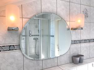uma casa de banho com um grande espelho redondo na parede em Stadtgarten Gotha em Gotha