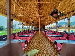 a row of tables and chairs in a building at Hampi Natures Cottage in New Hampi