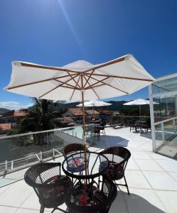 einen Tisch und Stühle mit Sonnenschirm auf einer Terrasse in der Unterkunft Espaço Rose Costa in Niterói