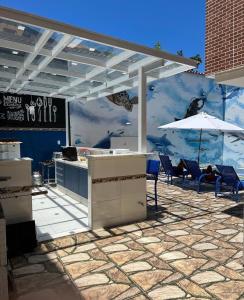 eine Terrasse mit Tischen, Stühlen und einem Sonnenschirm in der Unterkunft Espaço Rose Costa in Niterói