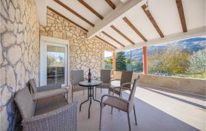 a porch with a table and chairs and a stone wall at Awesome Home In Dugopolje With Outdoor Swimming Pool in Dugopolje