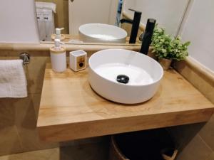 a white bowl sink on a wooden counter in a bathroom at Apartamentos Serrallo in Granada