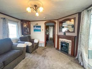 a living room with a couch and a fireplace at Lovely Caravan With Large Decking At Southview Holiday Park Ref 33108s in Skegness