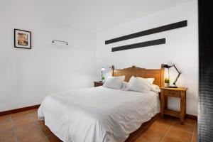 een slaapkamer met een wit bed en een lamp op een tafel bij Finca Emblemática - Nº1 Tisalaya in La Vegueta +18 foto's