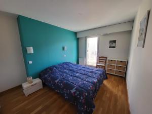 1 dormitorio con cama y pared azul en Appartement Les Sables-d'Olonne, 3 pièces, 4 personnes - FR-1-92-880, en Les Sables-dʼOlonne