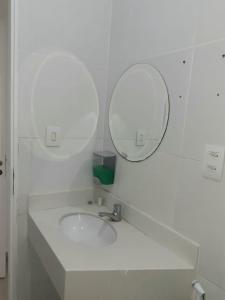 a white bathroom with a sink and two mirrors at Suíte Privativa em Casa de Vila in Rio de Janeiro