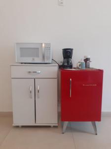 a microwave sitting on top of a red refrigerator at Suíte Privativa em Casa de Vila in Rio de Janeiro