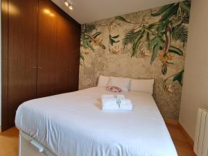 een slaapkamer met een groot wit bed met bloemenbehang bij Ático de Lujo en el Centro de Burgos in Burgos