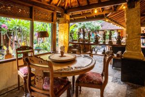 a dining room with a table and chairs and a large window at Lombok Stanley Garden Villas in Montongbuwoh