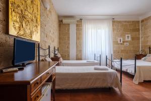 1 Schlafzimmer mit 2 Betten und einem Schreibtisch mit einem TV in der Unterkunft Tenuta San Trifone Corbezzolo in Seclì