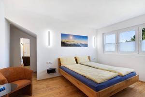 een witte slaapkamer met een bed en een stoel bij Wolf's Apartment Rheintal in Renchen