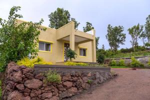 a house with a stone wall in front of it at Hill View Bungalow,Mahabaleshwar With Private Swimming Pool in Mahabaleshwar