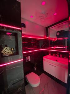 a red lighted bathroom with a toilet and a sink at Studio Prestige, île des pêcheurs, vue port in Cap d'Agde