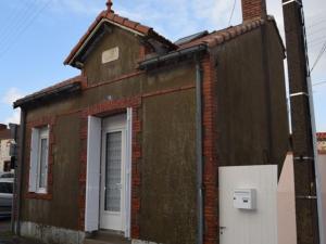 um velho edifício de tijolos com uma porta branca em Maison La Bernerie-en-Retz, 3 pièces, 4 personnes - FR-1-612-17 em La Bernerie-en-Retz