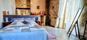 a bedroom with a bed in a room with a brick wall at Gîte Kiwi - Domaine du Pi geonnier de Saint-Vincent in Bourran