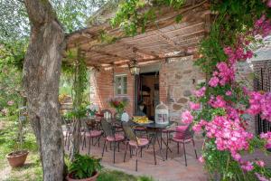 un patio con mesa, sillas y flores en Romantic farmhouse villa Pallina to sleep 5 guests, en Aquilea