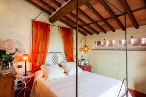 1 dormitorio con cama con dosel y cortina de color naranja en Romantic farmhouse villa Pallina to sleep 5 guests, en Aquilea