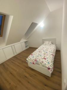 een witte slaapkamer met een bed op zolder bij Apartman Harmonija in Inđija