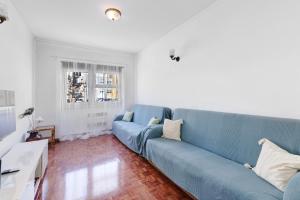 sala de estar con sofá azul y ventana en Cozy and Vintage Apartment, en Carcavelos