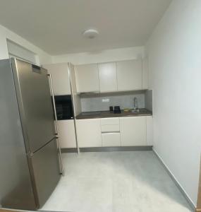 Elle comprend une petite cuisine avec des placards blancs et un réfrigérateur. dans l'établissement Apartman Harmonija, à Inđija
