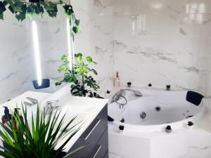 a bathroom with a white tub and a plant at L'Élégant in Douvaine