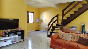 uma sala de estar com um sofá e uma televisão de ecrã plano em Casa de praia para família - 3 quartos - acomoda até 10 pessoas em Tramandaí