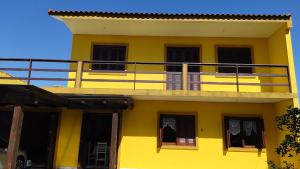 een geel gebouw met een balkon erboven bij Casa de praia para família - 3 quartos - acomoda até 10 pessoas in Tramandaí